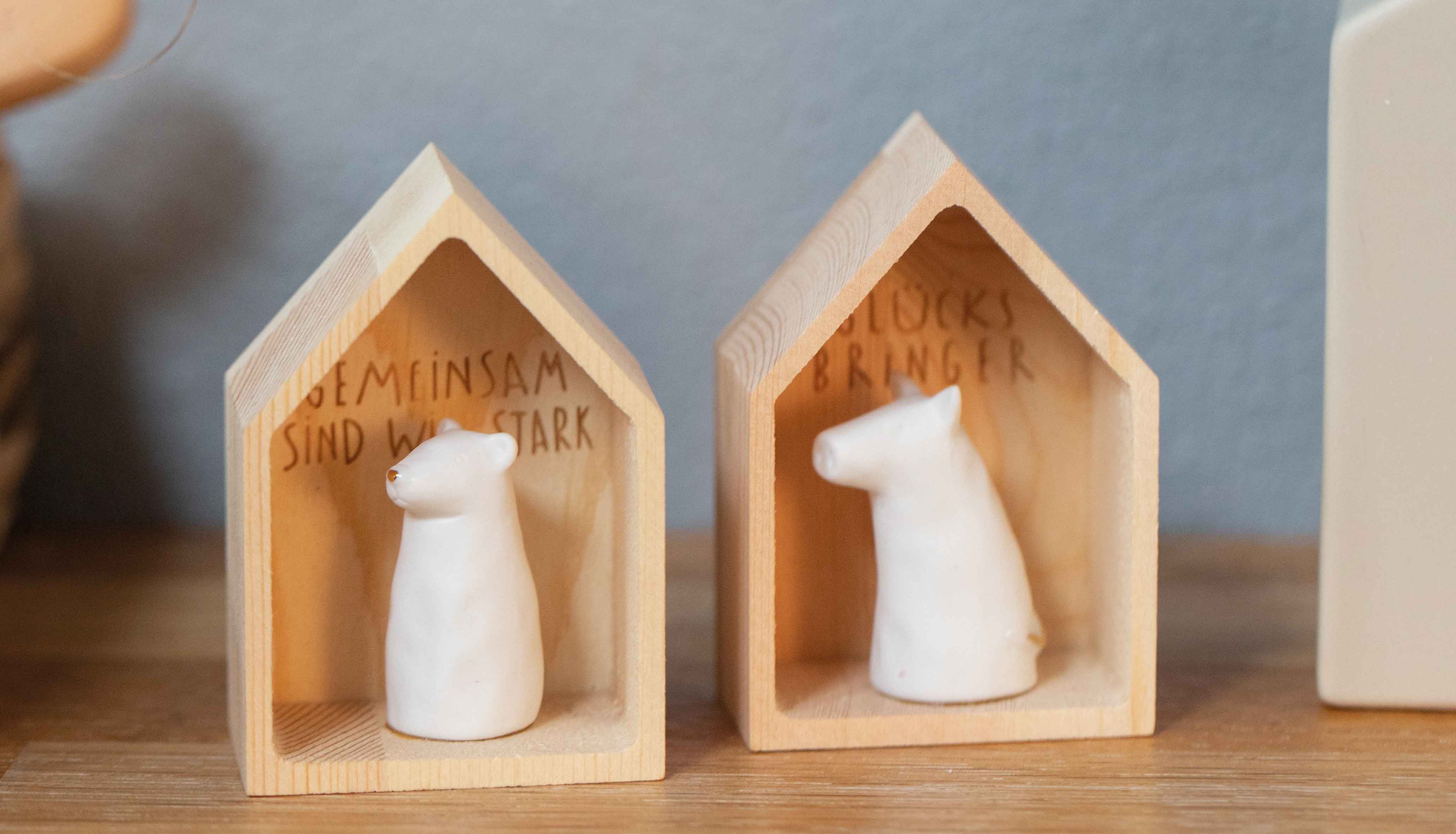Das Foto zeigt zwei Geschenkartikel aus einem Holzhäuschen mit Porzellantier